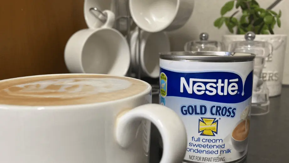 Condensed milk coffee in white mug in front of can of condensed milk.