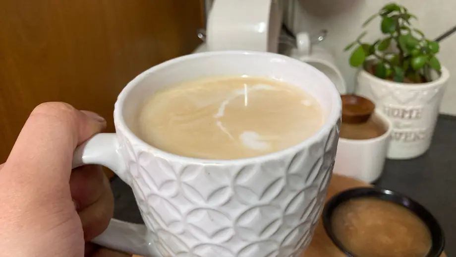 Me holding a caramel Latte in white textured mug.