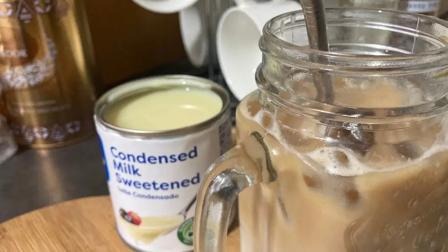 Condensed milk iced coffee and condensed milk on wooden surface