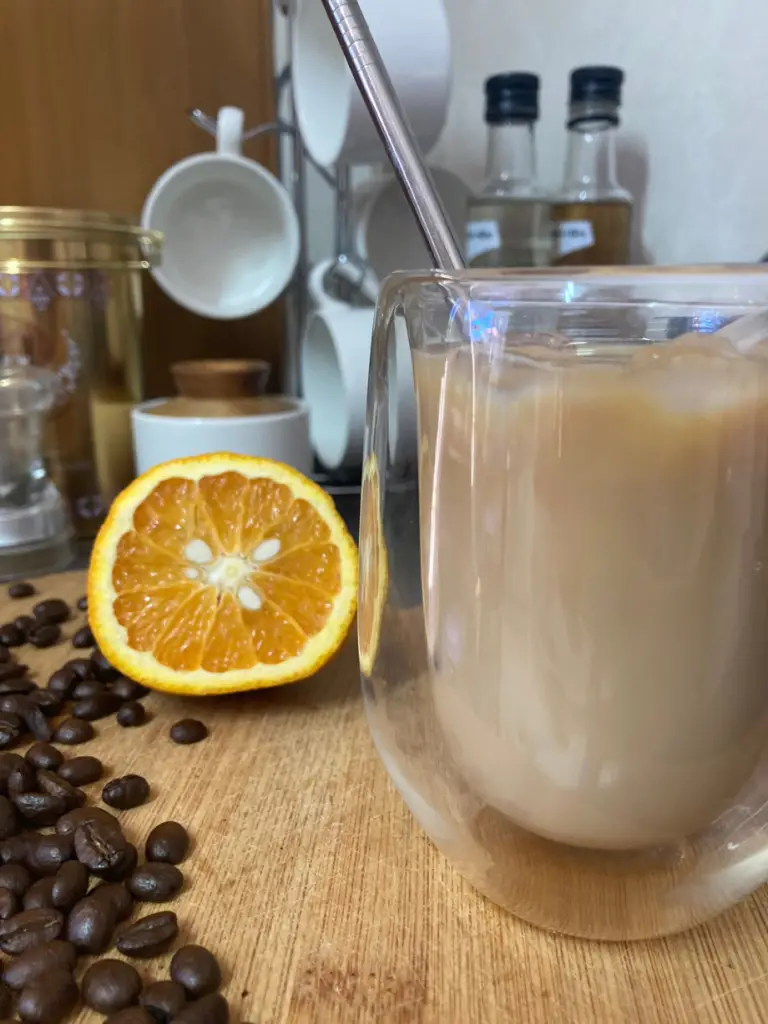 Orange iced coffee in a double walled glass.