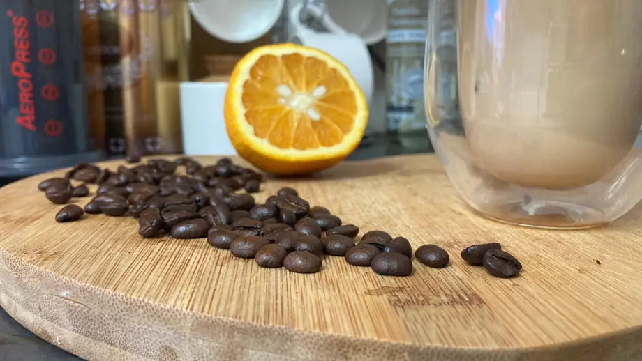 Orange and coffee beans on a wooden surface.