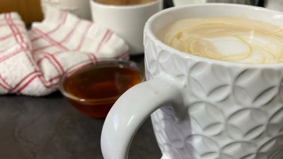 Honey latte in a textured white mug with honey drizzled over.