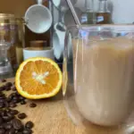 Orange iced coffee in a double walled glass.